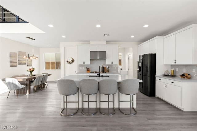 3058 Casarano Ct, Henderson, NV 89044 - kitchen featuring black refrigerator with ice dispenser, a breakfast bar area, backsplash, light wood-type flooring, and recessed lighting
