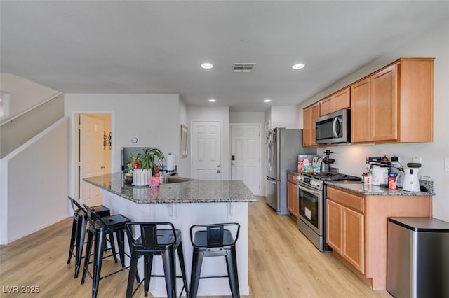 8733 Autumn Teal Ave, Las Vegas, NV 89178 - kitchen with appliances with stainless steel finishes, light wood-type flooring, a breakfast bar, an island with sink, and recessed lighting