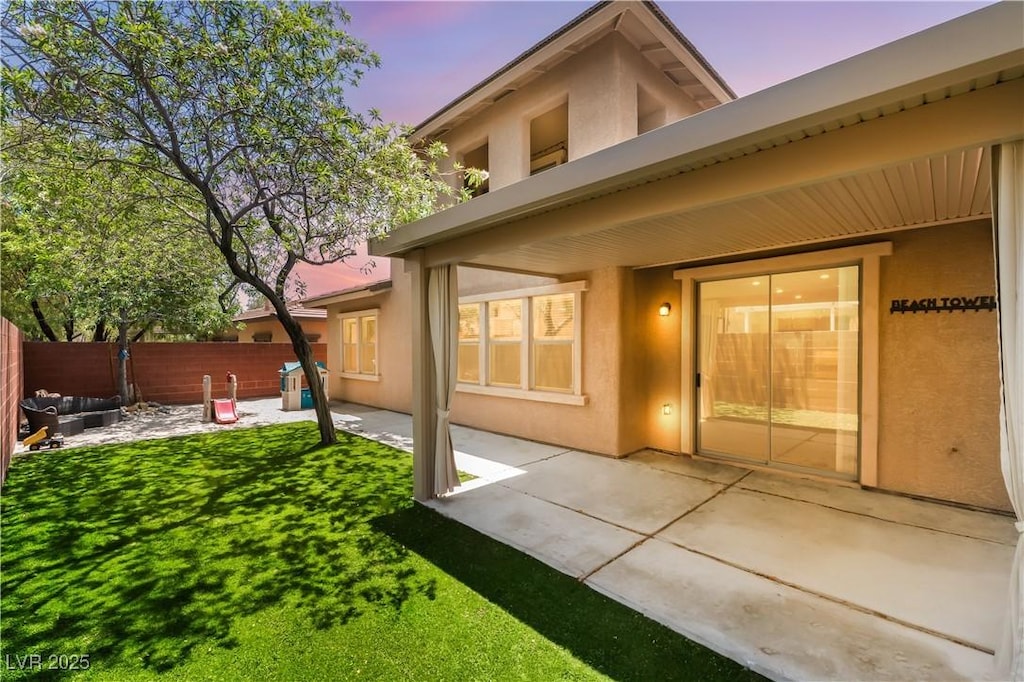 5568 Table Top Ln, Las Vegas, NV 89135 - back of house at dusk with stucco siding, a fenced backyard, and a patio area