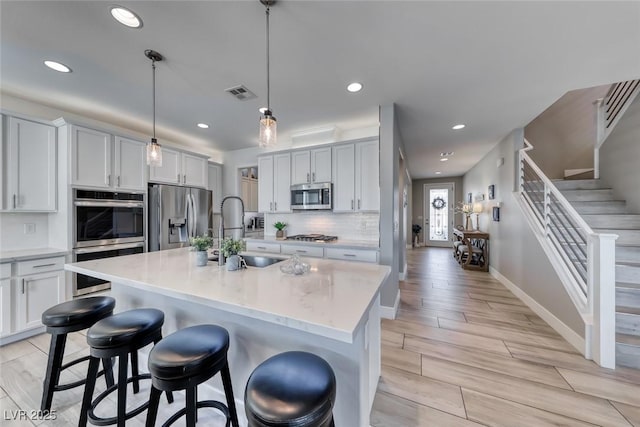 1523 Great Sands St, Boulder City, NV 89005 - kitchen with stainless steel appliances, recessed lighting, decorative backsplash, a breakfast bar area, and a kitchen island with sink