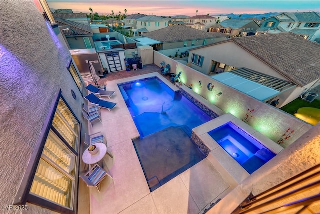 1523 Great Sands St, Boulder City, NV 89005 - pool at dusk with a fenced backyard, a residential view, a pool with connected hot tub, and a patio