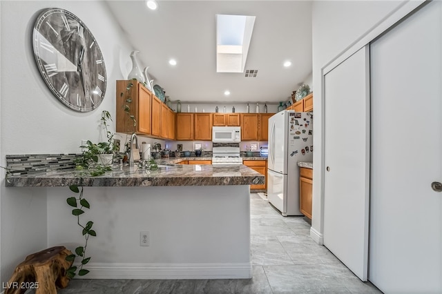 3495 Eagle Bend St, Las Vegas, NV 89122 - kitchen with white appliances, a skylight, a peninsula, recessed lighting, and brown cabinetry