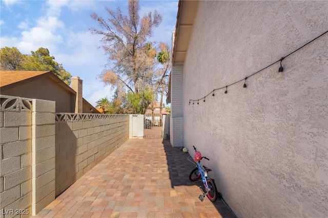 327 Fuente Dr, Henderson, NV 89014 - view of side of home featuring stucco siding, a patio area, and a gate