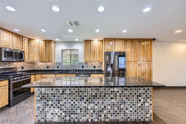 3557 Wayne Cir, Las Vegas, NV 89121 - kitchen featuring appliances with stainless steel finishes, a center island, dark stone countertops, decorative backsplash, and recessed lighting