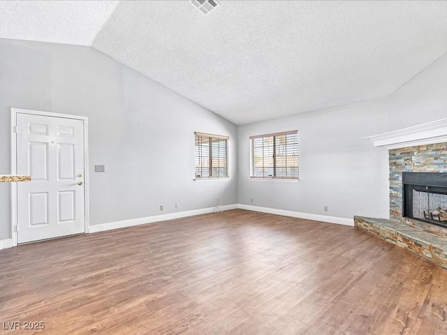 5861 Medallion Dr Unit 202, Las Vegas, NV 89122 - unfurnished living room with vaulted ceiling, a textured ceiling, wood finished floors, and a stone fireplace