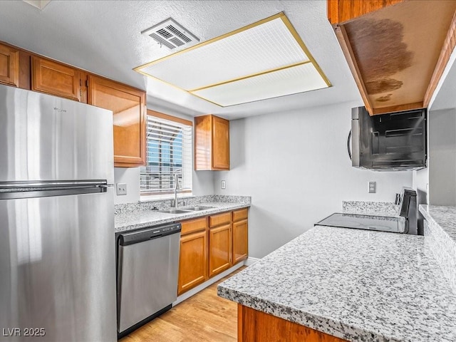 5861 Medallion Dr Unit 202, Las Vegas, NV 89122 - kitchen featuring stainless steel appliances, brown cabinets, and light wood-style floors