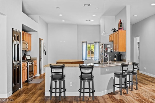 4212 Helens Pouroff Ave, North Las Vegas, NV 89085 - kitchen with stainless steel appliances, a peninsula, dark wood finished floors, light countertops, and recessed lighting