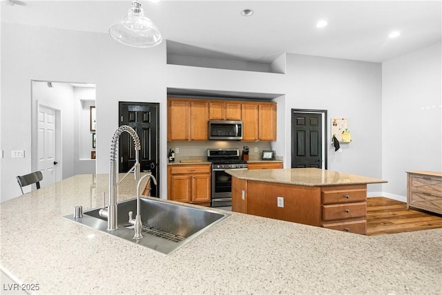 4212 Helens Pouroff Ave, North Las Vegas, NV 89085 - kitchen with appliances with stainless steel finishes, a kitchen island, brown cabinets, wood finished floors, and recessed lighting