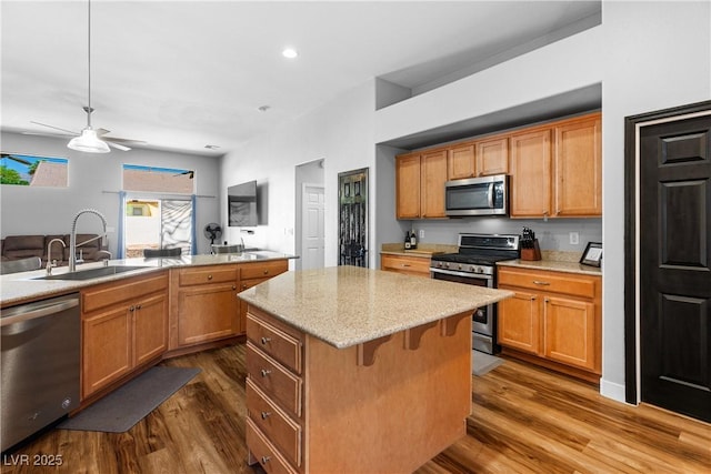 4212 Helens Pouroff Ave, North Las Vegas, NV 89085 - kitchen with stainless steel appliances, a center island, dark wood-style floors, a ceiling fan, and light stone counters