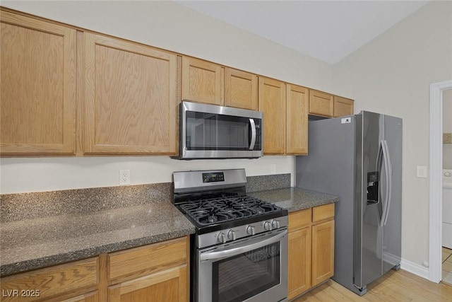 5512 Goldbrush St, Las Vegas, NV 89130 - kitchen with stainless steel appliances, dark stone counters, light wood-style flooring, and washer / clothes dryer