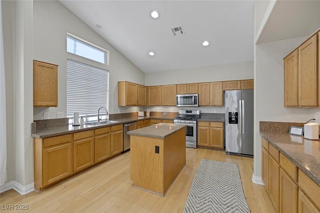 5512 Goldbrush St, Las Vegas, NV 89130 - kitchen with stainless steel appliances, a center island, dark stone counters, high vaulted ceiling, and light wood-style flooring