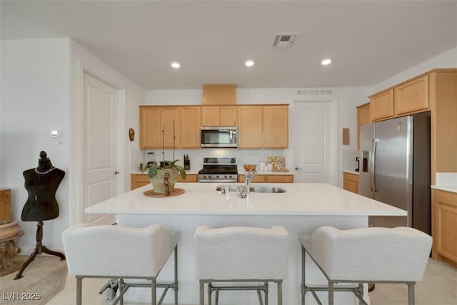 2261 Cold Canyon Ave, North Las Vegas, NV 89086 - kitchen with stainless steel appliances, a kitchen bar, a center island with sink, light countertops, and light brown cabinets