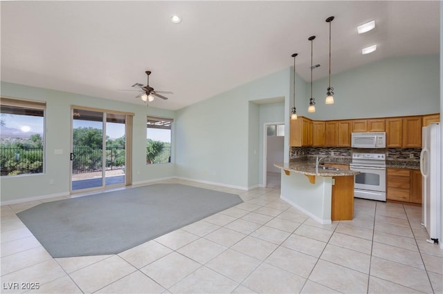 693 Hagens Aly, Mesquite, NV 89027 - kitchen with white appliances, a peninsula, lofted ceiling, light tile patterned floors, and backsplash