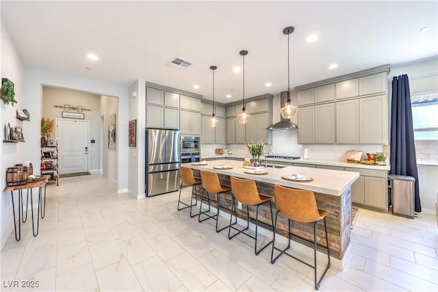 879 Klamath Springs St, Henderson, NV 89011 - kitchen featuring wall chimney exhaust hood, stainless steel appliances, gray cabinetry, light countertops, and a breakfast bar