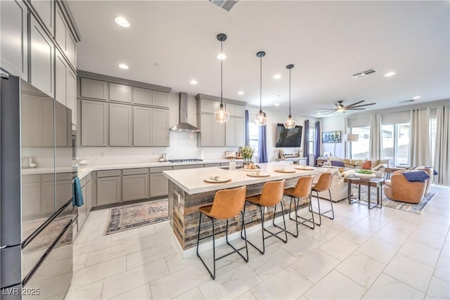 879 Klamath Springs St, Henderson, NV 89011 - kitchen with high quality fridge, gray cabinetry, wall chimney range hood, a kitchen bar, and light countertops