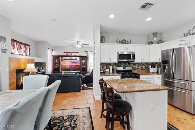 10918 Avenzano St, Las Vegas, NV 89141 - kitchen with stainless steel appliances, light tile patterned floors, white cabinetry, a kitchen island, and tasteful backsplash