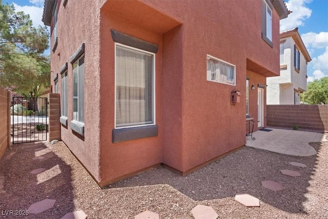 10918 Avenzano St, Las Vegas, NV 89141 - view of property exterior featuring stucco siding, a gate, and a patio area