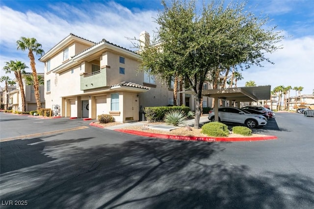 7163 S Durango Dr Unit 302, Las Vegas, NV 89113 - view of front of home featuring stucco siding, covered parking, and a chimney