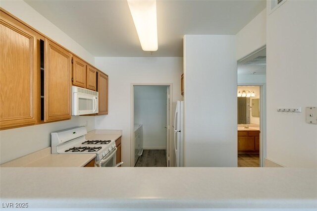 7163 S Durango Dr Unit 302, Las Vegas, NV 89113 - kitchen featuring white appliances, light countertops, washer and dryer, and wood finished floors