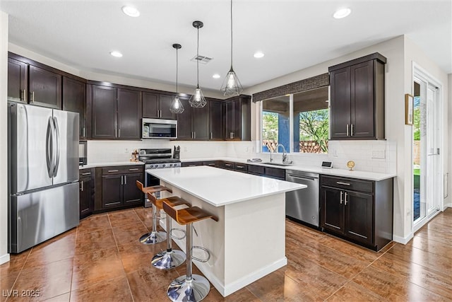7017 Pearl Hilltop Ct, Las Vegas, NV 89148 - kitchen featuring appliances with stainless steel finishes, a center island, dark brown cabinetry, a kitchen bar, and recessed lighting