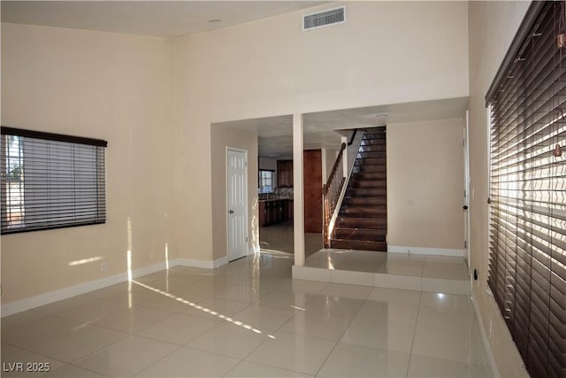 1340 Lucky St, Las Vegas, NV 89104 - empty room with light tile patterned flooring, stairs, a towering ceiling, and plenty of natural light
