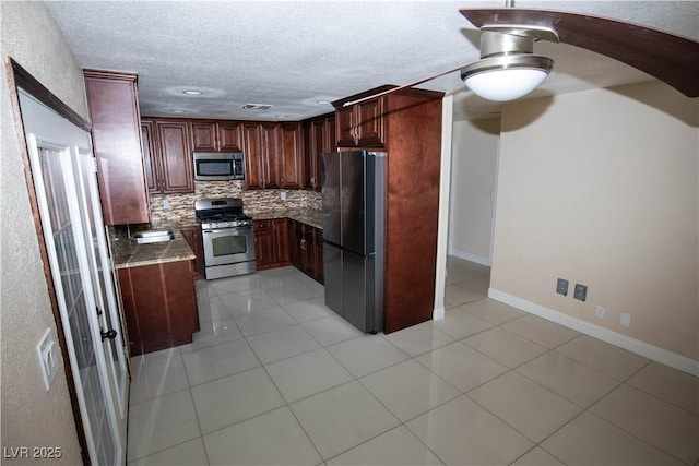 1340 Lucky St, Las Vegas, NV 89104 - kitchen featuring stainless steel appliances, tasteful backsplash, light tile patterned floors, dark stone countertops, and a ceiling fan