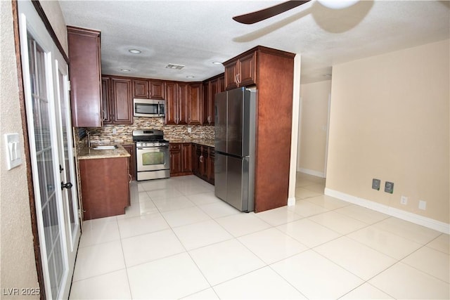 1340 Lucky St, Las Vegas, NV 89104 - kitchen featuring stainless steel appliances, a ceiling fan, backsplash, light stone counters, and light tile patterned floors