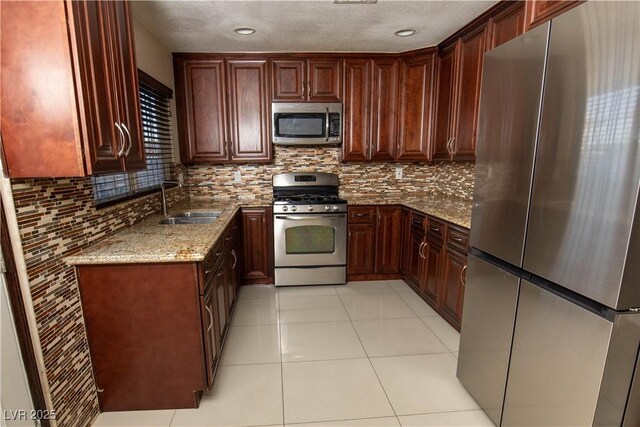 1340 Lucky St, Las Vegas, NV 89104 - kitchen with appliances with stainless steel finishes, light stone counters, decorative backsplash, light tile patterned floors, and a textured ceiling