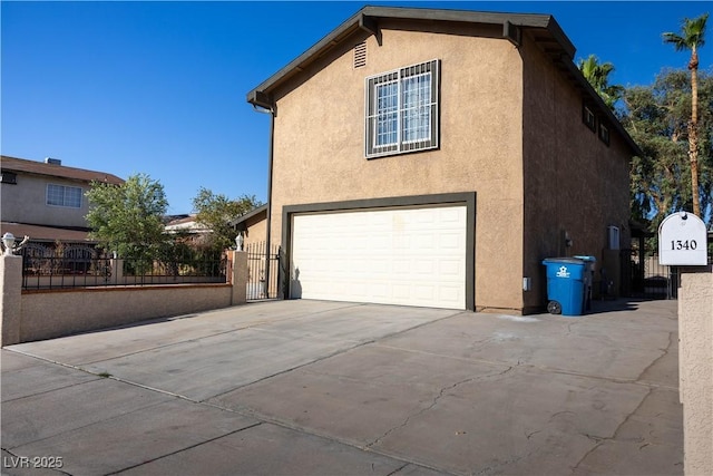 1340 Lucky St, Las Vegas, NV 89104 - view of side of property featuring an attached garage, stucco siding, a gate, and concrete driveway
