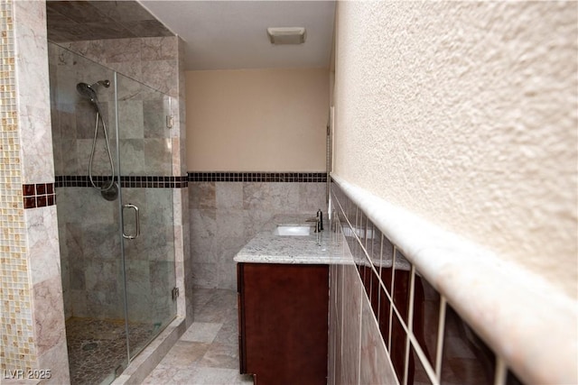 1340 Lucky St, Las Vegas, NV 89104 - bathroom featuring tile walls, a shower stall, vanity, and a wainscoted wall