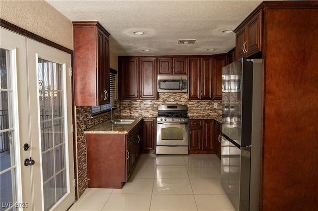 1340 Lucky St, Las Vegas, NV 89104 - kitchen featuring stainless steel appliances, dark stone countertops, tasteful backsplash, a textured ceiling, and light tile patterned floors