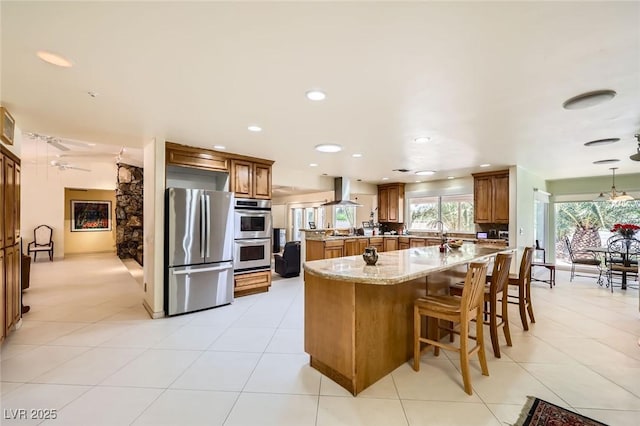 2770 La Casita Ave, Las Vegas, NV 89120 - kitchen featuring appliances with stainless steel finishes, wall chimney exhaust hood, brown cabinetry, light stone counters, and recessed lighting