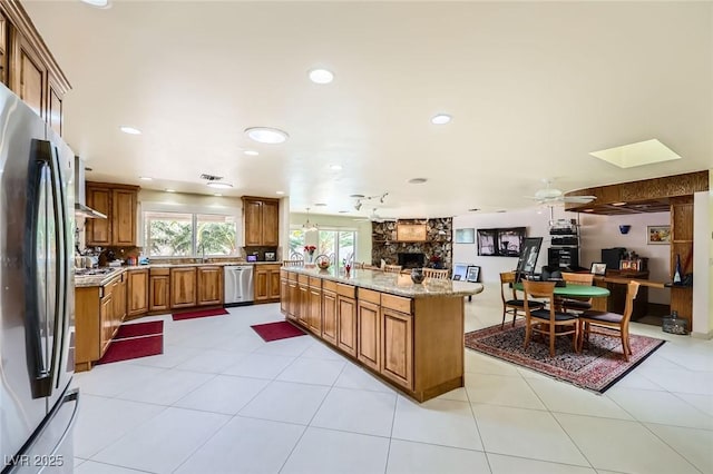 2770 La Casita Ave, Las Vegas, NV 89120 - kitchen with appliances with stainless steel finishes, brown cabinets, a stone fireplace, ceiling fan, and a desk