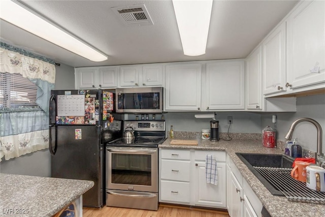 5301 River Glen Dr Unit 205, Las Vegas, NV 89103 - kitchen with appliances with stainless steel finishes, white cabinets, light wood finished floors, and light countertops