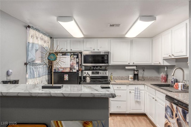 5301 River Glen Dr Unit 205, Las Vegas, NV 89103 - kitchen featuring stainless steel appliances, white cabinetry, and light stone countertops