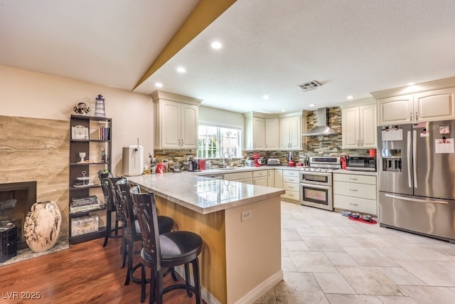 4095 Ridgewood Ave, Las Vegas, NV 89120 - kitchen with appliances with stainless steel finishes, wall chimney range hood, a peninsula, backsplash, and recessed lighting