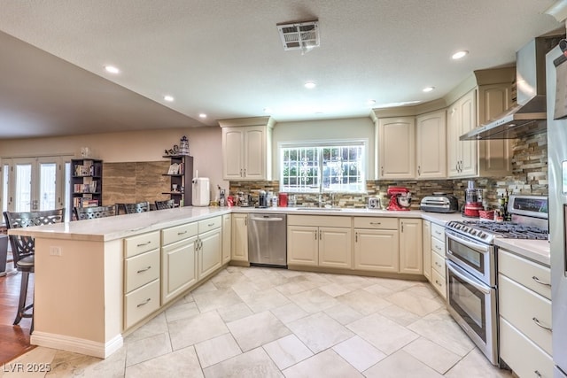 4095 Ridgewood Ave, Las Vegas, NV 89120 - kitchen with stainless steel appliances, a peninsula, wall chimney range hood, decorative backsplash, and a kitchen breakfast bar