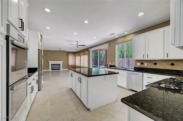 229 N Buteo Woods Ln, Las Vegas, NV 89144 - kitchen featuring appliances with stainless steel finishes, ceiling fan, a kitchen island, white cabinetry, and open floor plan