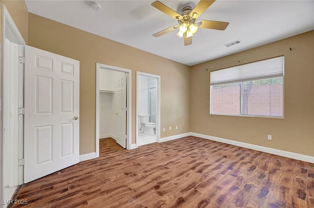 229 N Buteo Woods Ln, Las Vegas, NV 89144 - unfurnished bedroom featuring wood finished floors, connected bathroom, a ceiling fan, a walk in closet, and a closet