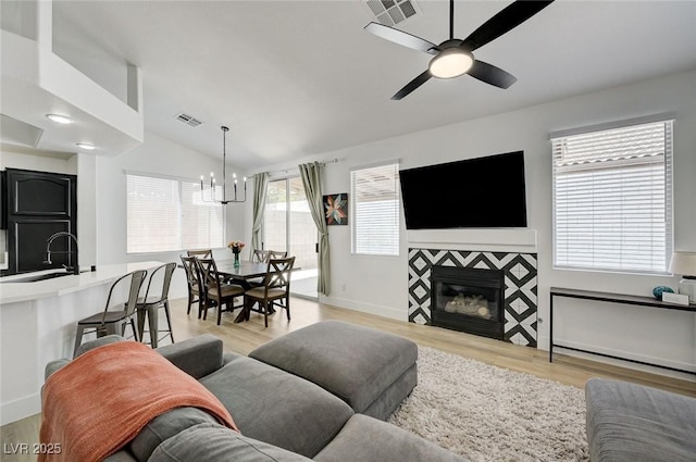 201 Crown Imperial St, Henderson, NV 89074 - living area featuring light wood finished floors, ceiling fan, lofted ceiling, a chandelier, and a fireplace