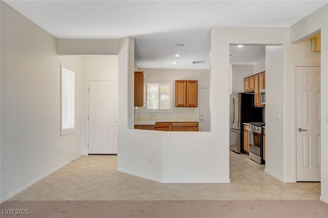 2508 Chasma Dr, Henderson, NV 89044 - kitchen featuring appliances with stainless steel finishes, brown cabinetry, light tile patterned floors, light countertops, and recessed lighting