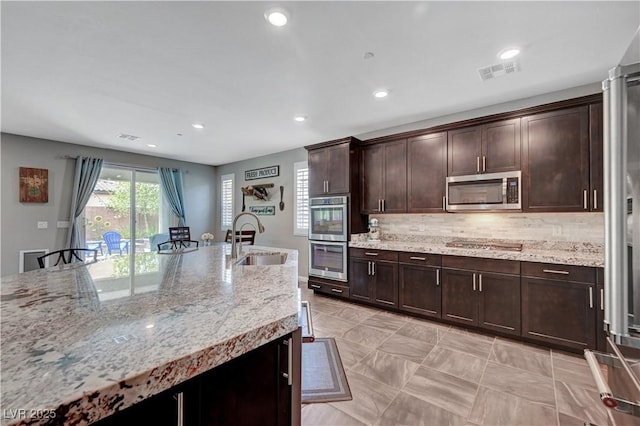 2433 Amatrice St, Henderson, NV 89044 - kitchen featuring stainless steel appliances, backsplash, dark brown cabinets, recessed lighting, and light stone countertops