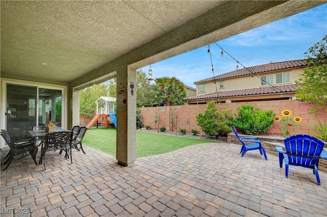 2433 Amatrice St, Henderson, NV 89044 - fenced backyard featuring a patio area, a playground, and outdoor dining space