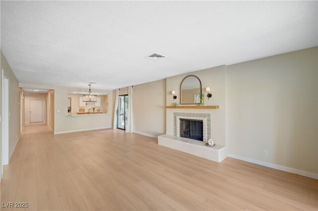 1905 Plaza Del Padre, Las Vegas, NV 89102 - unfurnished living room featuring a chandelier, a fireplace, and light wood-style floors