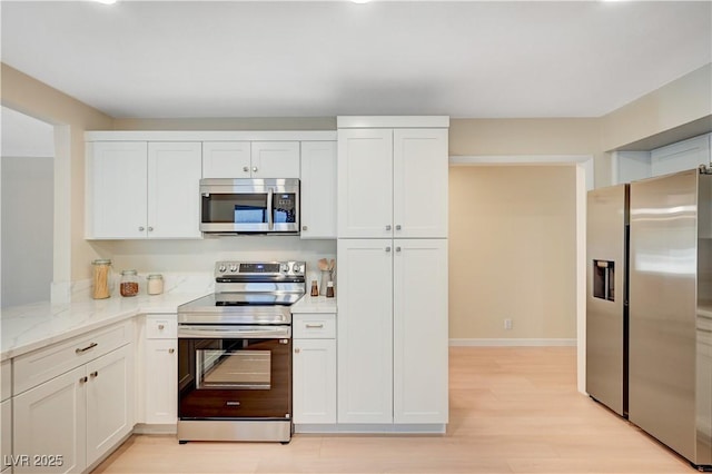 1905 Plaza Del Padre, Las Vegas, NV 89102 - kitchen with stainless steel appliances, light wood-style floors, white cabinetry, and light stone countertops
