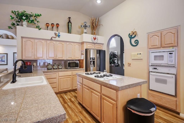 816 Sandsprings St, Henderson, NV 89011 - kitchen with appliances with stainless steel finishes, light brown cabinetry, vaulted ceiling, light wood finished floors, and a center island