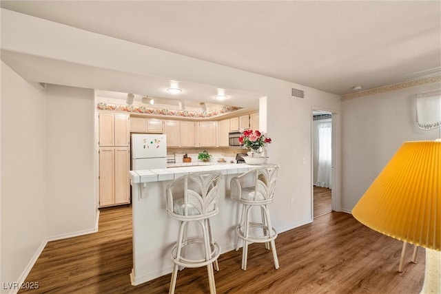 7950 W Flamingo Rd Unit 1024, Las Vegas, NV 89147 - kitchen with freestanding refrigerator, tile counters, a peninsula, wood finished floors, and stainless steel microwave