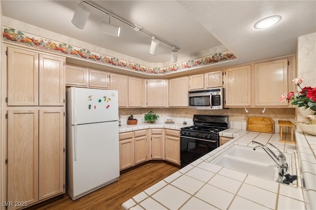 7950 W Flamingo Rd Unit 1024, Las Vegas, NV 89147 - kitchen featuring freestanding refrigerator, stainless steel microwave, tile countertops, black gas range, and light brown cabinets