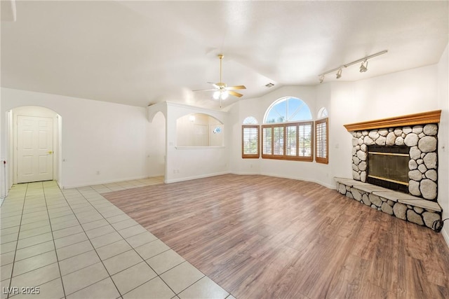 901 E Jaybird St, Pahrump, NV 89048 - unfurnished living room with a ceiling fan, a fireplace, light wood-type flooring, arched walkways, and vaulted ceiling