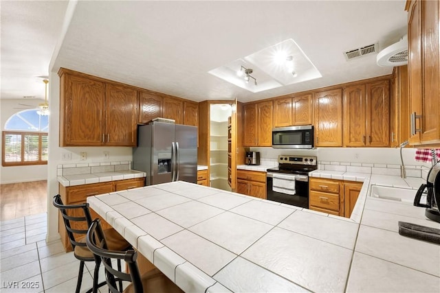 901 E Jaybird St, Pahrump, NV 89048 - kitchen featuring stainless steel appliances, a peninsula, light tile patterned floors, and tile counters